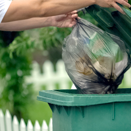 man dropping trash into bin